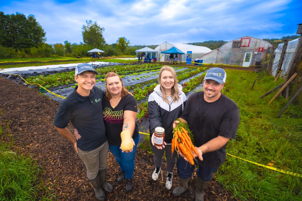 2 hommes et deux femmes montrant des légumes dans un champ