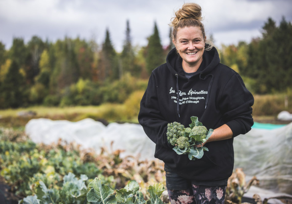 Une femme tenant un brocoli à la fin de l'été dans un champs